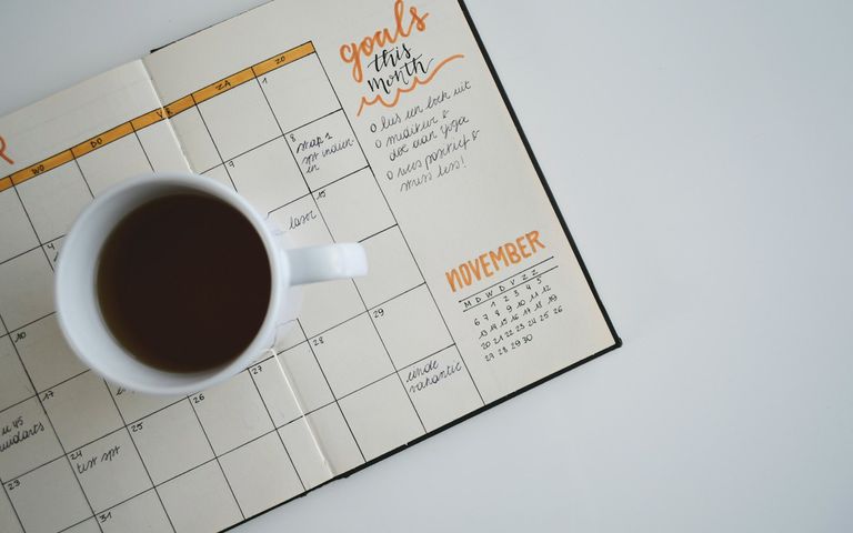 A calendar and coffee on a desk at the start of the day